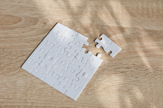 White puzzle pieces on a table with shadow from sunlight