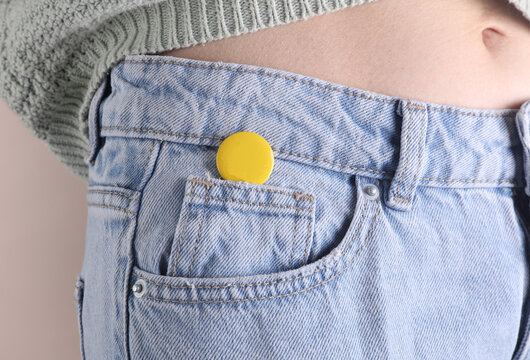 Yellow blank pin button on woman's jeans
