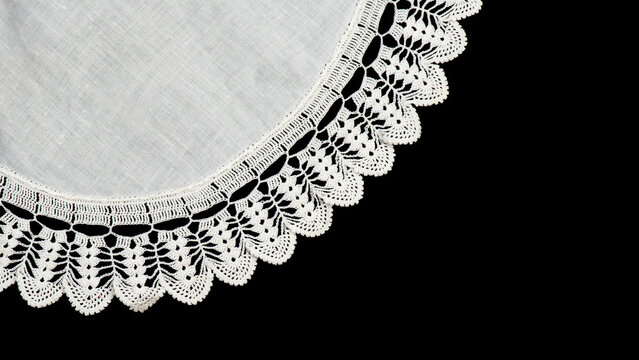 Round crochet lace doily isolated on black background, crocheted Grandma's Doily, detail of hand-crocheted embroidery, tablecloth, napkin border art design. Craft, vintage linen. Vintage table setting