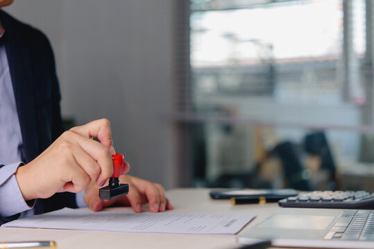 Document Stamping and Approval Process with Laptop and Office Paperwork for Business Verification Authorization and Administrative Workflow