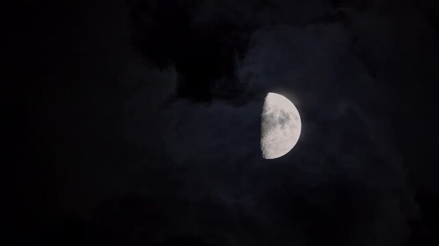 Half Moon Shining Through Dark Clouds at Night