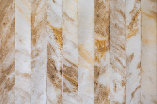 Beige Marble Effect Wall Tiles with Natural Veining. Beige and brown marble effect tiles arranged in vertical strips with soft natural veining and a neutral stone texture.