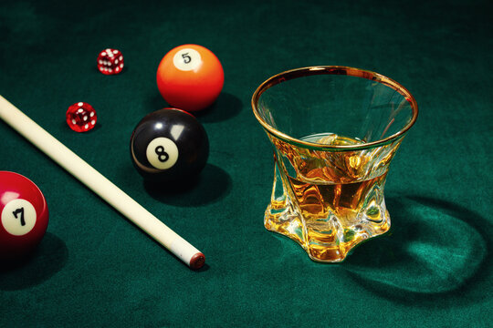 There is a glass of whiskey on the billiard table, there are no people,