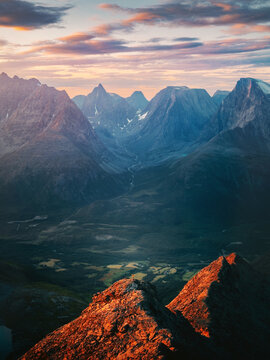 Sunset mountains in Norway aerial view adventurer man climbing solo standing on peak tiny traveler showing scale, active summer vacations healthy lifestyle extreme trip outdoor trekking in Lyngen Alps