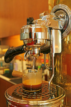 Fresh espresso shot pouring from a professional lever machine into a glass