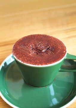 A cup of delicious Italian Marocchino coffee with cocoa powder on a wooden table