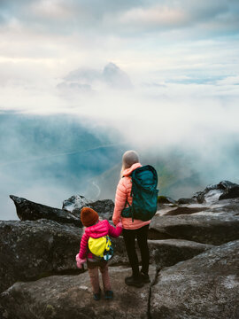 Mother and child backpacking together in Norway climbing foggy Segla mountain top, family travel vacation hiking outdoors adventure lifestyle active holidays parent mom and kid explore Senja together