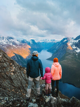 Parents and child hiking in Norway family travel adventure overlooking sunset mountain lake outdoor, father mother and kid on active lifestyle vacation bonding nature exploration Romsdal eco tourism