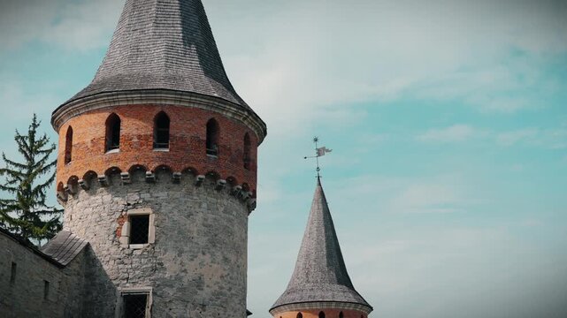 KAMIANETS-PODILSKYI, UKRAINE - SEPTEMBER 11, 2026: Close-up of a stone castle tower with red brick crenellations and a weathervane at the Old Castle