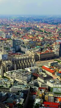 Vertical video. Milan, Italy. The Duomo di Milano and Galleria Vittorio Emanuele II, Drone footage over terracotta rooftops and the cathedral's forest of Gothic spires under an overcast sky.. Drone f