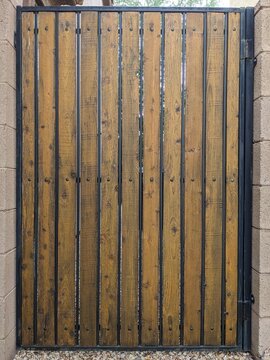 Dark stained wooden planks set within a black metal frame of the garden gate