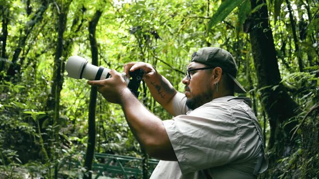 Latino wildlife photographer with professional equipment filming and taking photos in the Costa Rica rainforest. Tourism and adventure