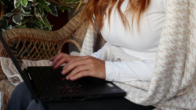 Close-up of female freelancer typing on laptop while working from home on balcony