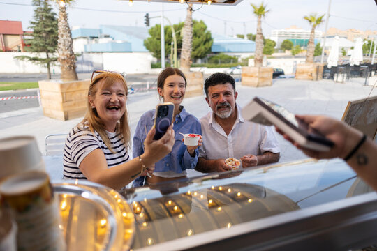 Family enjoying dessert and taking selfie at street food truck