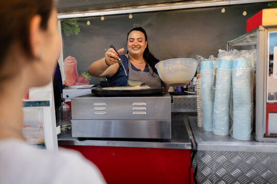 Woman preparing fresh crepe at food stall