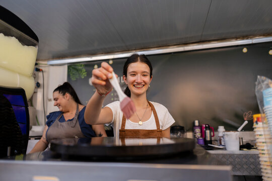 Young woman smiling, preparing food in a food truck