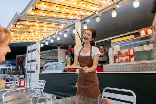 Young server delivering food at outdoor food truck restaurant