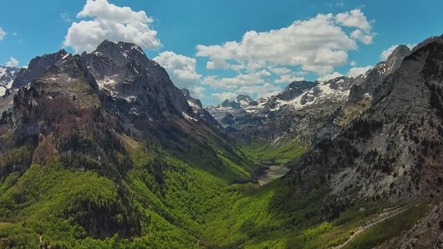 Aerial view of amazing rocky mountains in snow and green valley, Prokletie park, Montenegro and Albania, 4k