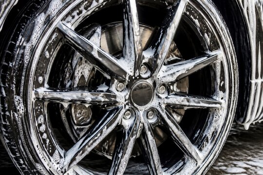 Alloy wheel covered in soap foam during car exterior wash