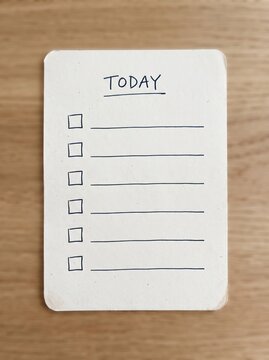 Blank daily checklist paper with handwritten header on a wooden desk surface