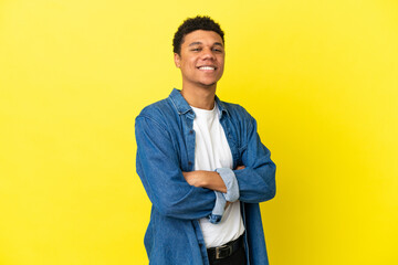 Young African American man isolated on yellow background with arms crossed and looking forward