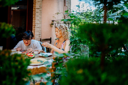 Mother and teenage son with Down syndrome having breakfast together on lush garden terrace