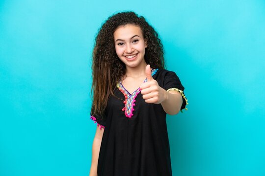 Young Arab woman isolated on blue background with thumbs up because something good has happened