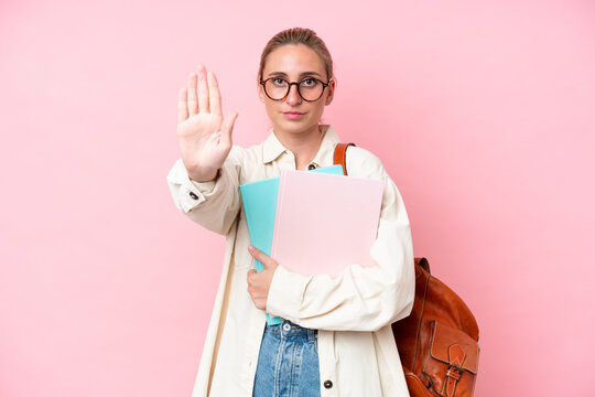 Young student caucasian woman isolated on pink background making stop gesture