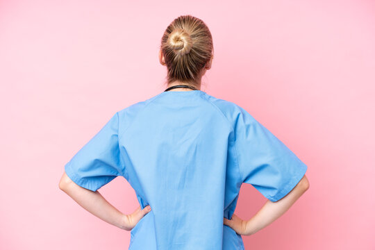 Young surgeon nurse woman isolated on pink background in back position