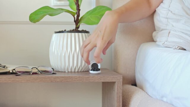 Woman takes reusable earplugs from small case beside bed and closes it