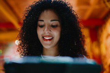 Close up of happy young woman smiling while looking down at digital tablet screen in creative indoor studio, tech savvy youth and distance online learning or freelance lifestyle concept © BullRun