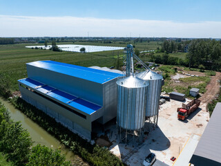 aerial view of modern grain silos and blue factory building in rural area © zhu difeng
