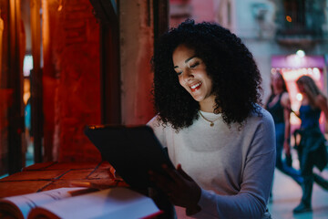 Happy young woman looking at digital tablet screen and smiling inside cozy illuminated cafe, cheerful female student or creative freelancer working remotely on design project portrait © BullRun