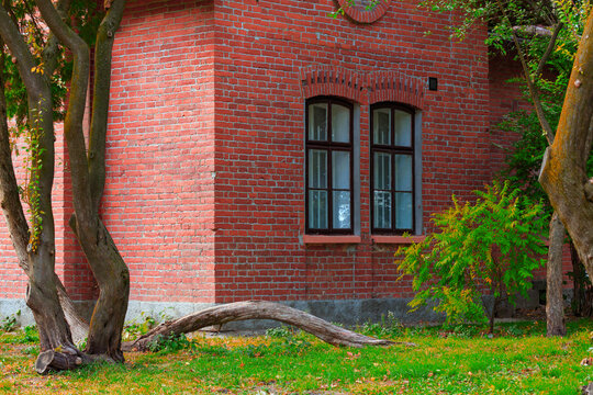 Old brick building corner with arched windows and lush green garden idyllic tranquil green back yard of cottage core aesthetic peaceful atmosphere