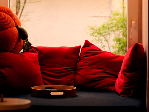 Cozy window seat with plush red pillows and a decorative pumpkin