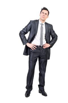 Full body of pondering male manager in suit standing with hands on waist and looking up with expression of doubt, transparent background