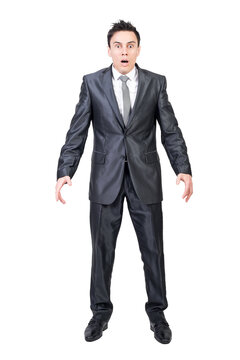 Full length of shocked young male manager in formal suit and tie with dark hair looking at camera with opened mouth