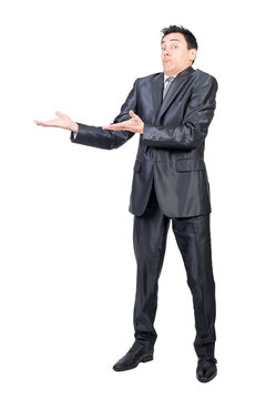 Full body of amazed male in formal suit pointing aside with hands while promoting ad isolated on transparent background in studio