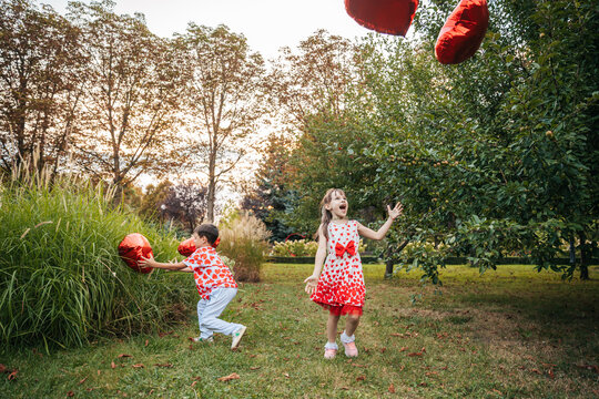 Children Play With Heart-Shaped Pillows in a Garden During a Summer Holiday, Celebrating Love and Joy on Valentine's Day