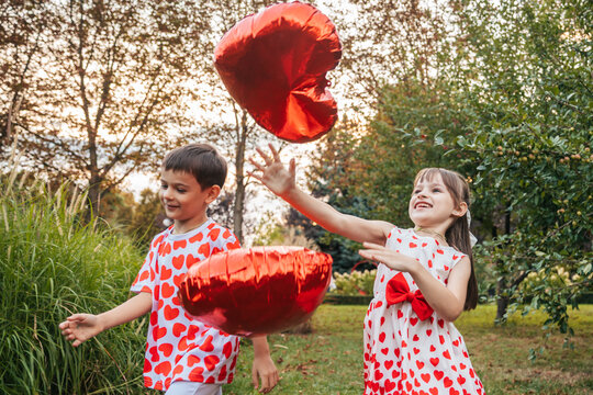 Children Play With Heart-Shaped Balloons During a Summer Holiday Celebration in a Garden Filled With Greenery