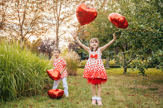 Children Celebrate Valentine's Day With Red Heart Balloons in a Sunny Outdoor Location During Summer Holidays