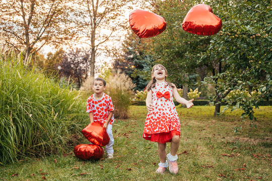 Children Play With Red Heart-Shaped Pillows in a Garden During Summer Holidays, Celebrating Love and Joy on Valentine's Day