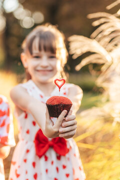 Children Celebrate Valentine's Day With a Red Cupcake Decorated With a Heart Symbol in a Summer Outdoor Setting