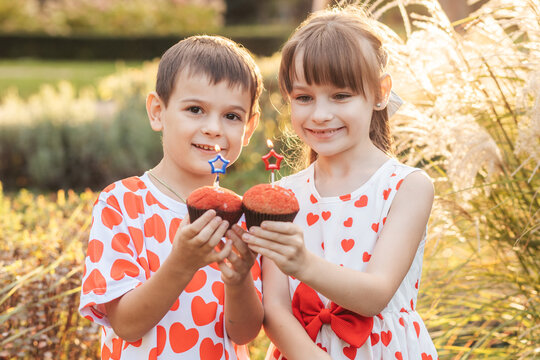 Children Enjoy Cupcakes in a Garden During Summer Holiday Celebrating Valentine's Day With Red Hearts