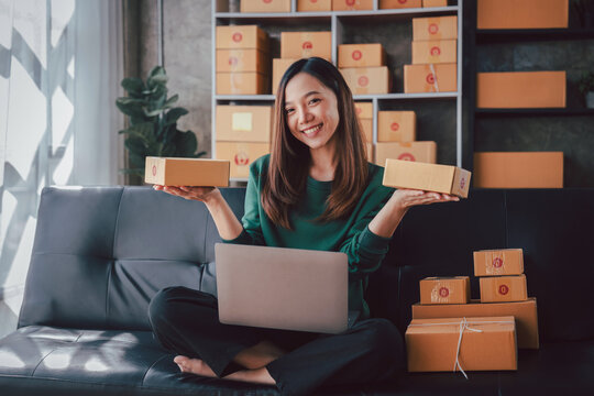 Asian Women Running Small Business From Home Using Laptop Holdin