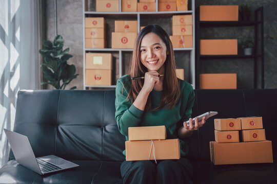 Asian Woman Managing Online Business, Packaging Boxes, and Check