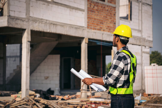 Asian Adult Engineer Overseeing Construction Site with Blueprint
