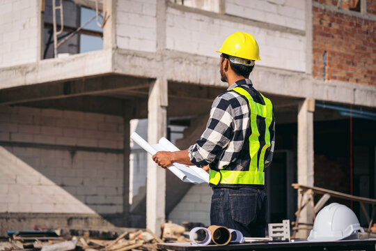 Construction Worker Inspecting Building Blueprint at Constructio