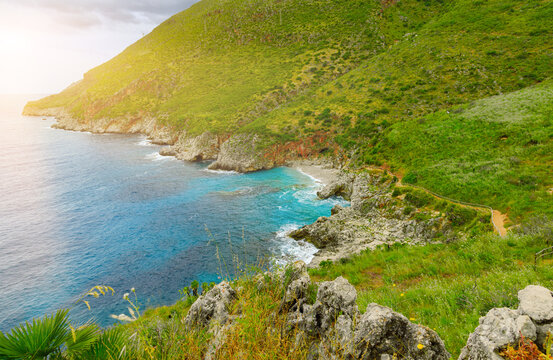 Lush green hills meet the turquoise sea along a rugged coastline