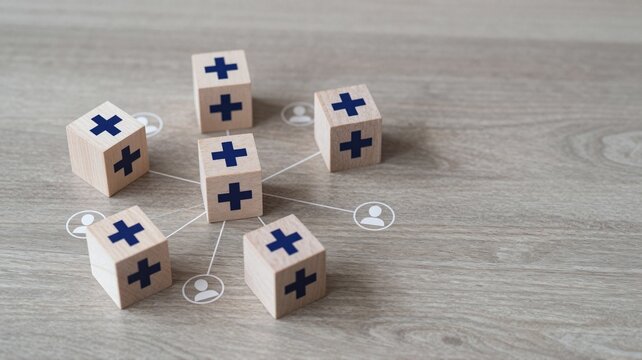 Wooden blocks with plus signs and human icons connected in a network on a table